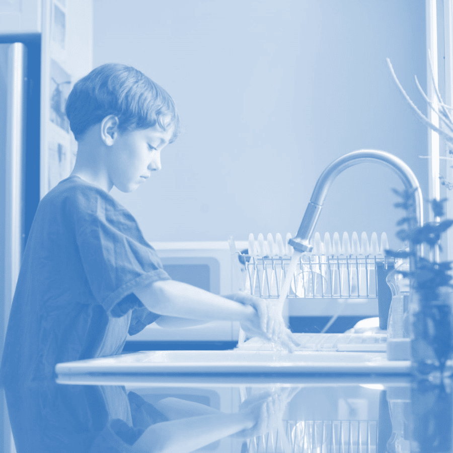 A boy washing his hands at the kitchen sink